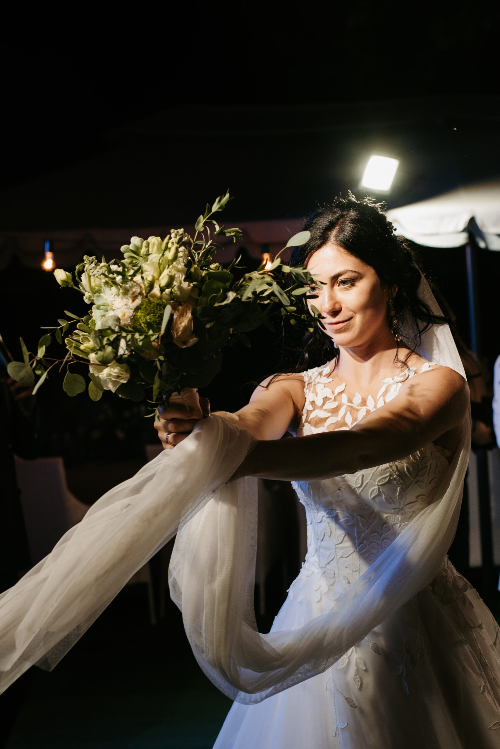 bride in a white dress throws a wedding bouquet to her unmarried girlfriends
