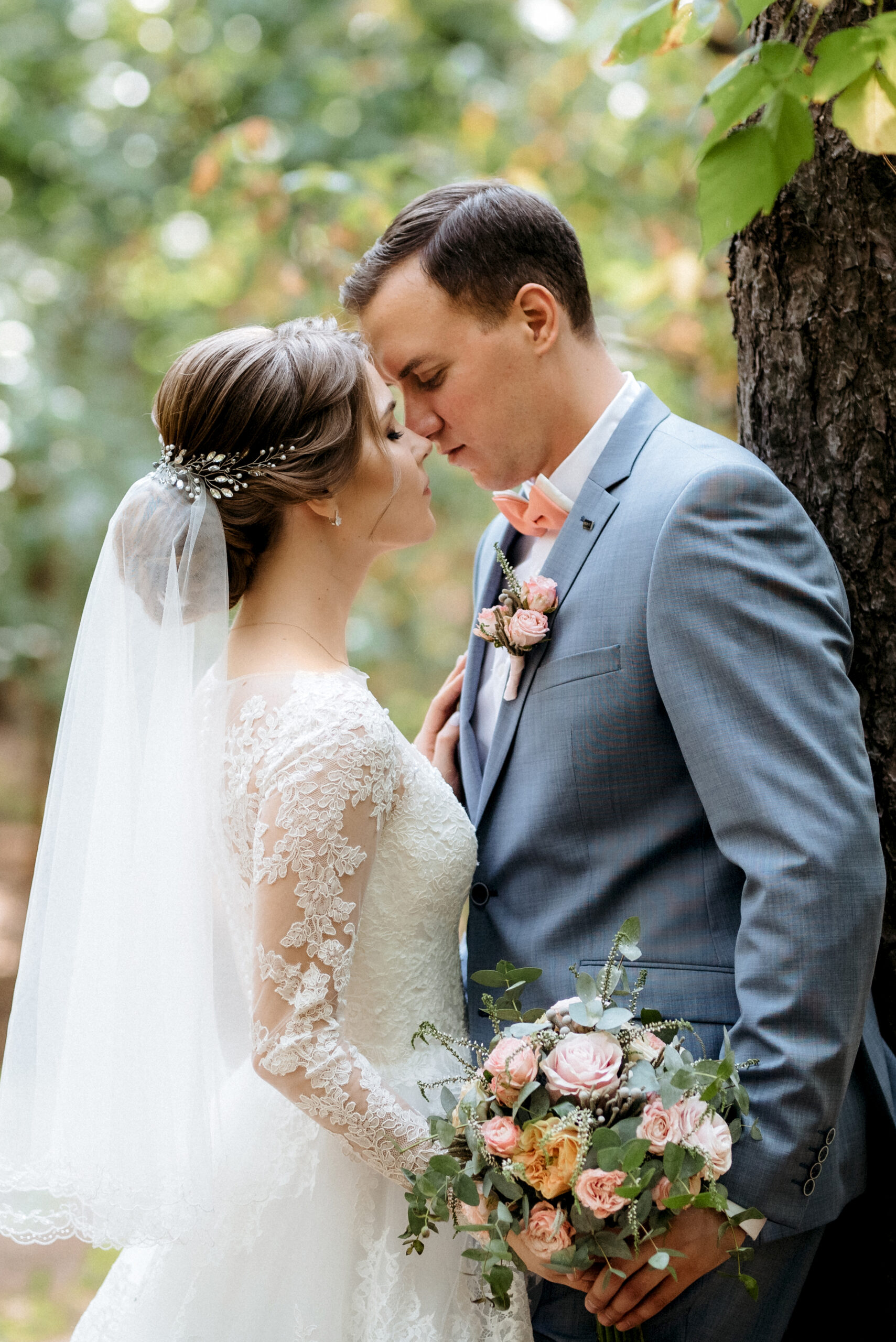 portrait of an elegant groom in a blue suit in a deciduous forest with a bouquet