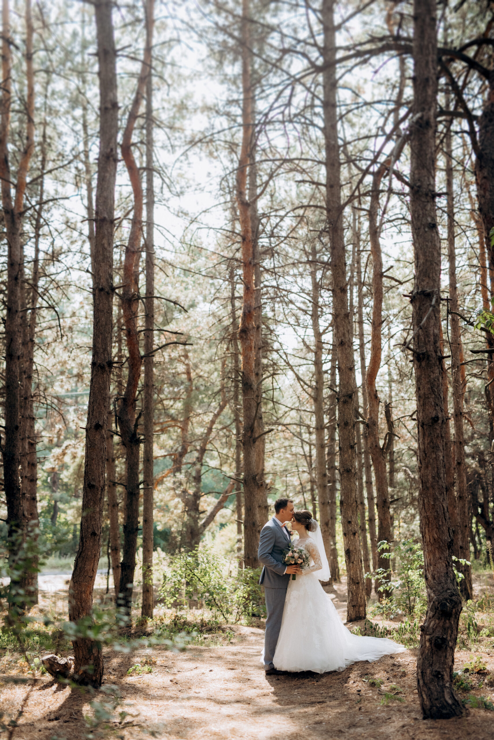 portrait of an elegant groom in a blue suit in a deciduous forest with a bouquet