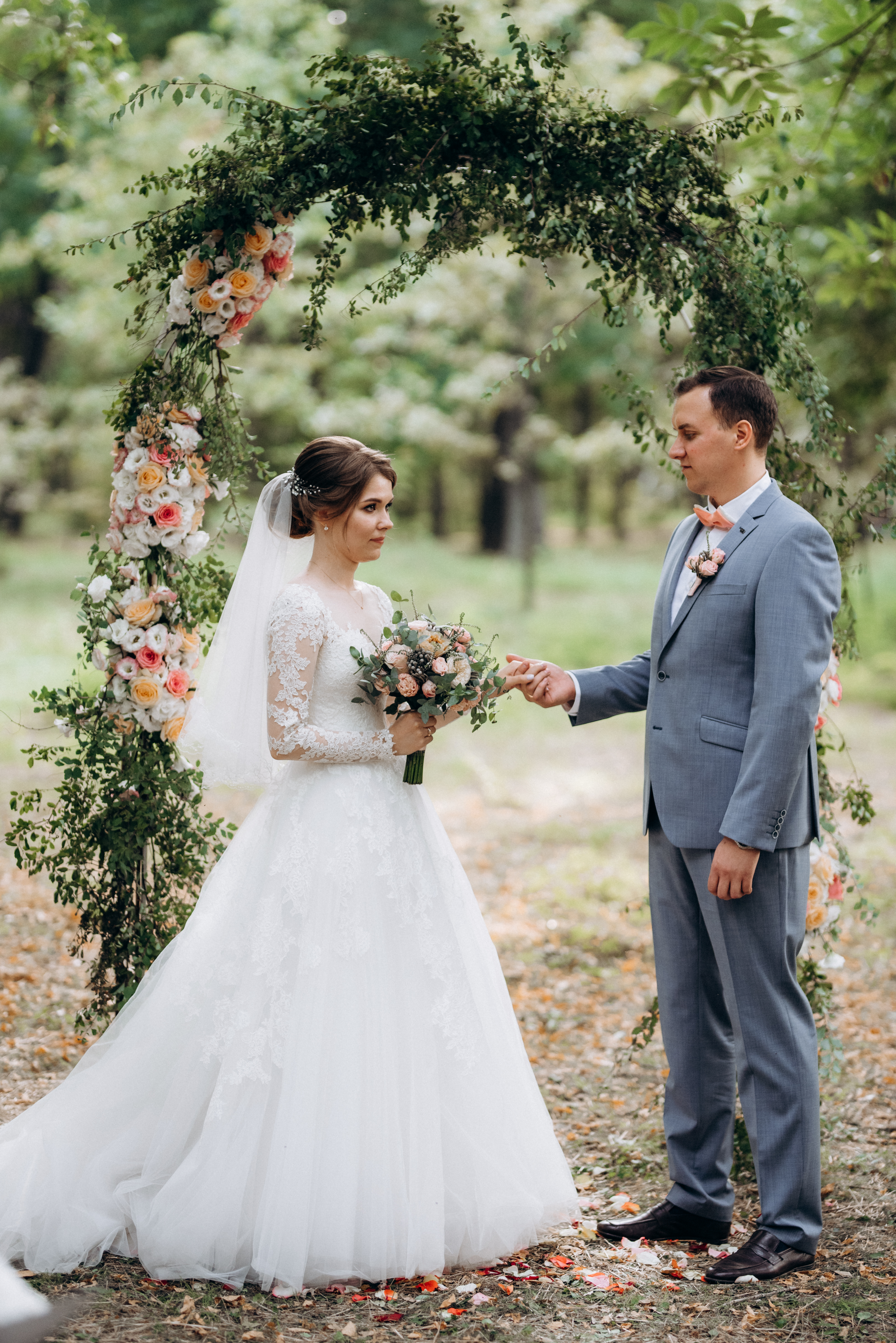 wedding ceremony of the marriage of a guy and a girl against the backdrop of an arch on a forest path