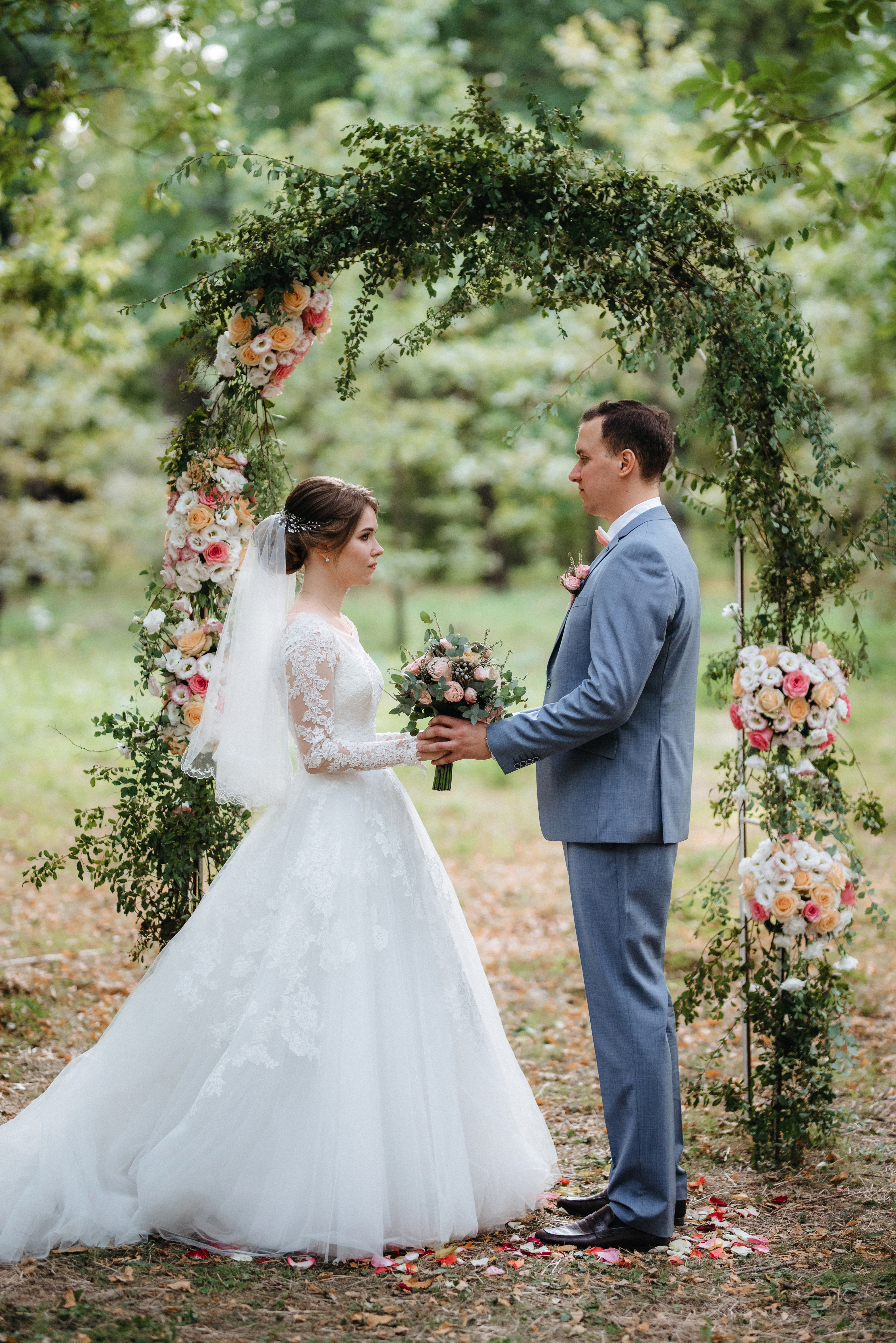 wedding ceremony of the marriage of a guy and a girl against the backdrop of an arch on a forest path